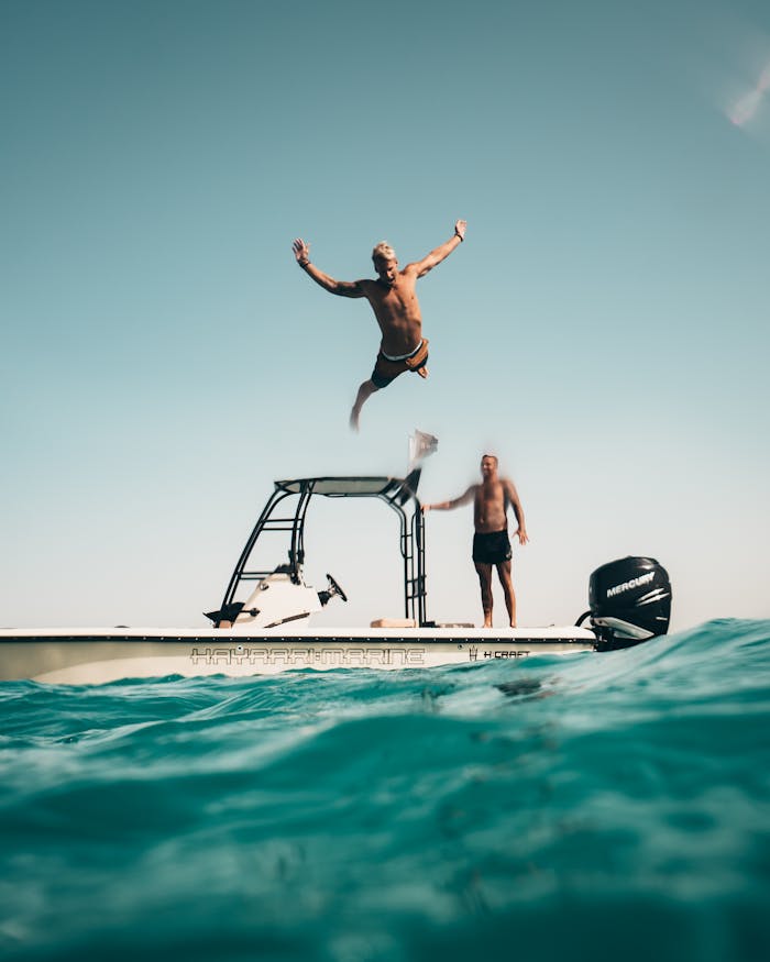 why-choose-us Two men enjoy a sunny adventure, jumping into the Abu Dhabi sea from a boat.