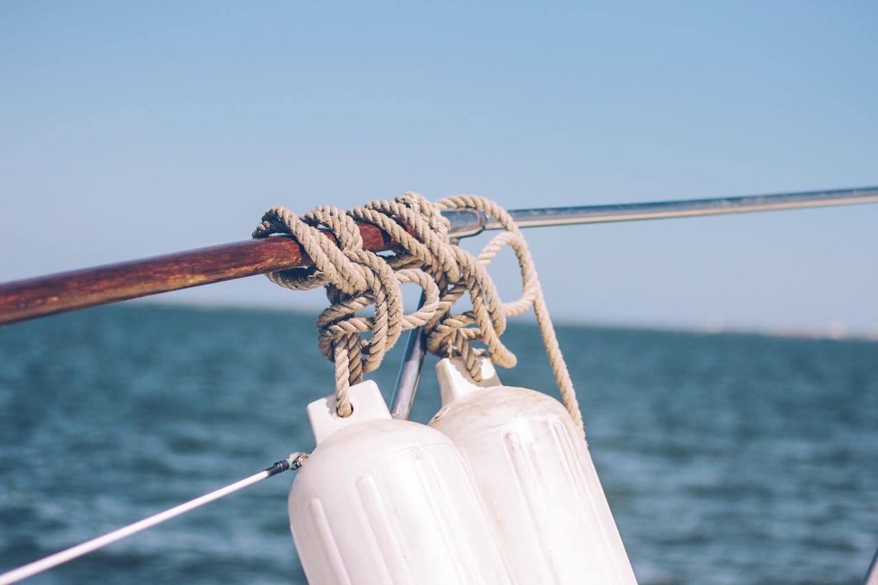 A detailed view of ropes and buoys on a boat over a calm ocean setting.
